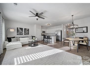 Bright, open-concept living area with modern furnishings, ceiling fan and eat-in kitchen in a neutrally decorated home at 116 Briana Marie Way, Indian Trail, NC 28079