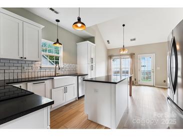 Bright kitchen with white cabinets, black countertops, stainless steel appliances, and hardwood floors at 1836 Danny Ct, Matthews, NC 28105