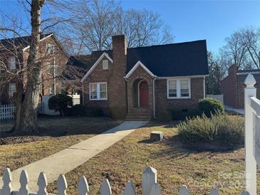 Charming brick home with a red front door and a well-maintained front yard with walkway and white picket fence at 2220 The Plz, Charlotte, NC 28205