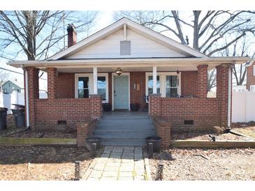 Charming brick home featuring a covered front porch with brick columns and a light blue front door at 604 Pearl Ave, Kannapolis, NC 28083