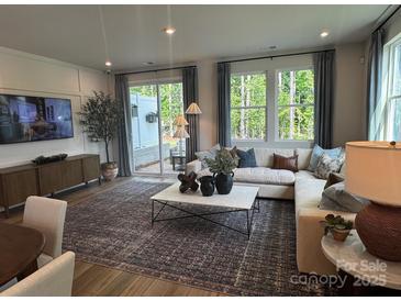 Bright living room features stylish decor, hardwood floors, and sliding glass doors to the patio at 9020 Northfield Crossing Dr, Charlotte, NC 28269