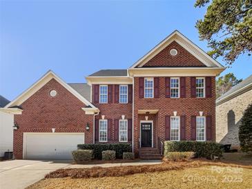 Charming two-story brick home with a well-maintained front yard and attached two car garage at 12025 Willingdon Rd, Huntersville, NC 28078