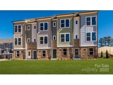 View of new construction townhomes featuring brick facade, modern design, and green lawn at 1311 Cerium Way, Charlotte, NC 28211