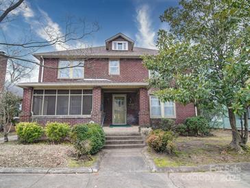 Charming two-story brick home featuring a screened front porch and mature landscaping at 113 2Nd St, Spencer, NC 28159