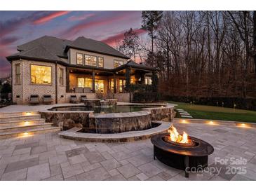 A gorgeous backyard featuring a patio, pool with waterfall, putting green, and fire pit, perfect for outdoor entertaining at 17639 Stuttgart Rd, Davidson, NC 28036