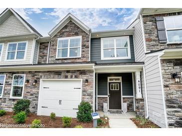 New two story townhome with stone accents, white garage door, and craftsman style front door at 4236 Black Ct # 234, Harrisburg, NC 28075