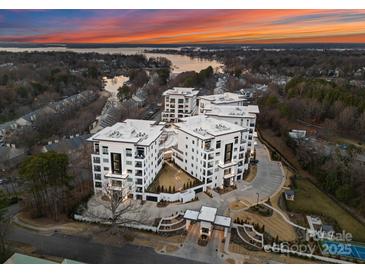 Luxury condo complex showcasing modern architecture, lush landscaping, and waterfront views at sunset at 19329 Watermark Dr # 551/552, Cornelius, NC 28031