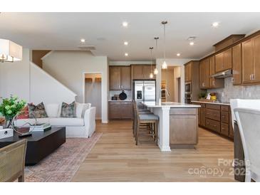 Open-concept living area featuring hardwood floors, stainless appliances, an island, and a cozy seating area at 5911 Wetlands Aly, Charlotte, NC 28215