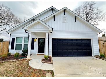 Charming home featuring a black garage door, a welcoming front door with a wreath, and well-maintained landscaping at 713 E Third Ave, Gastonia, NC 28054