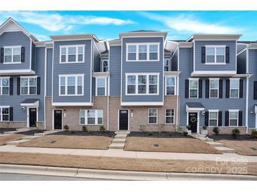 Charming townhome showcasing a well-maintained exterior with blue siding and brick accents at 112 August Ln, Matthews, NC 28104