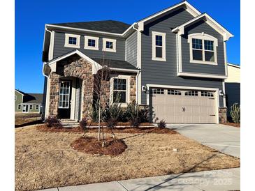 Charming two-story home with stone facade, gray siding, and attached two-car garage at 1463 Honey Trl, Monroe, NC 28112