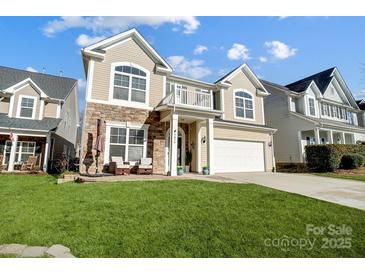 Charming two-story home featuring a stone facade, balcony, manicured lawn and an attached two car garage at 2024 Woodshorn Dr, Matthews, NC 28104