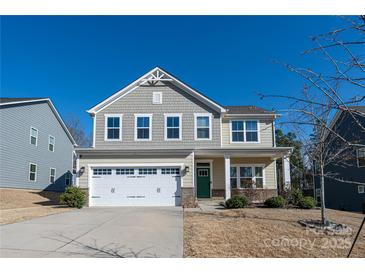 Two-story home with a two-car garage, neutral siding, green front door, and manicured landscaping at 10036 Paper Birch Dr, Charlotte, NC 28215