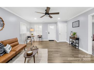 Bright living room featuring light gray walls, modern fan, and wood-look floors at 1075 Wellman St, Gastonia, NC 28054