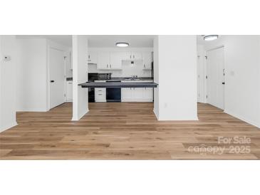 Bright kitchen with modern appliances, white cabinets, and a dark countertop breakfast bar at 1641 Arlyn Cir # A, Charlotte, NC 28213