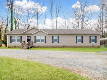 Ranch style home with gravel driveway, light siding, black shutters, and covered parking at 1005 Maywood St, Kannapolis, NC 28081