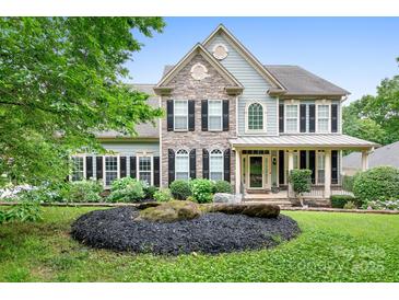 Charming two-story home featuring stone accents, black shutters, and a beautifully landscaped front yard at 7191 Grist Mill Ct, Denver, NC 28037