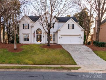 Charming two-story home with white brick, black shutters, landscaped yard, and a two car garage at 12813 Angel Oak Dr, Huntersville, NC 28078