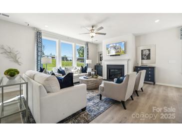 Comfortable living room with a fireplace, large windows, and neutral-colored furnishings at 1498 Hubert Graham Way, Tega Cay, SC 29708