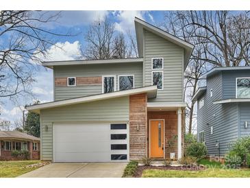 Contemporary two-story home featuring a stylish orange front door, white garage door, and unique architectural details at 3126 Creighton Dr, Charlotte, NC 28205