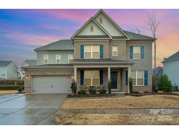 Charming two-story home with a brick and siding exterior, complemented by blue shutters and a well-manicured lawn at 8651 Shadetree St, Huntersville, NC 28078