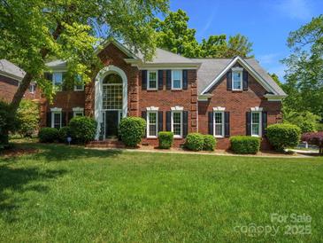 Beautiful brick two-story home featuring a large front yard, manicured bushes, and many windows at 9743 Aegean Ct, Huntersville, NC 28078