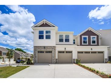 Beautiful townhome featuring stone accents, modern garage doors, and manicured landscaping at 14734 Tamarack Dr, Charlotte, NC 28278