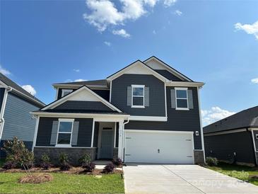 Charming two-story home featuring a two-car garage, stone accents, and a well-manicured front lawn at 330 Knotty Wood Dr # 67, Monroe, NC 28110