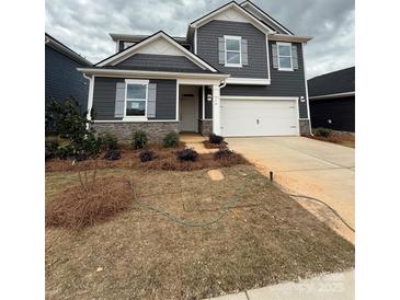 Charming two-story home featuring a manicured lawn, a two-car garage, and stone accents at 330 Knotty Wood Dr # 67, Monroe, NC 28110