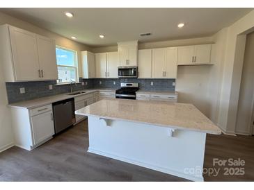 Bright kitchen boasts white cabinets, stainless appliances, gray backsplash and a large center island at 330 Knotty Wood Dr # 67, Monroe, NC 28110