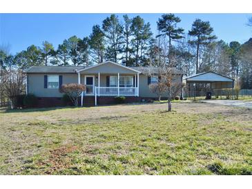 Charming single-story home features a covered front porch and a convenient carport, set against a backdrop of mature trees at 3640 Muskrat Se Pl, Concord, NC 28025