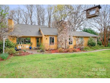 Charming single-Gathering home featuring a stone chimney, mature landscaping, and inviting front entrance at 8133 Strawberry Ln, Charlotte, NC 28277