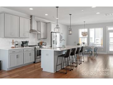 Modern kitchen features gray cabinets, stainless steel appliances, an island with barstool seating, and an adjacent dining area at 2014 Bryant Park Dr, Charlotte, NC 28208