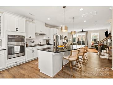 Bright kitchen with stainless steel appliances, black countertops, and a large island with bar seating at 613 Tudor Park Way, Charlotte, NC 28211