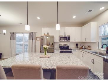 Bright kitchen features a large island with granite countertops, stainless steel appliances, and white cabinetry at 711 E 3Rd Ave, Gastonia, NC 28054