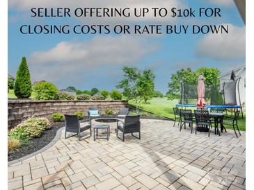 An outdoor patio boasts a fire pit, dining set, and trampoline, perfect for relaxing or entertaining in the backyard at 137 Tenth Green Ct, Statesville, NC 28677