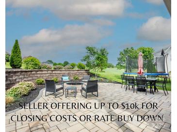 Outdoor patio with a fire pit, seating, dining area, trampoline, and manicured landscaping offers relaxation and entertainment at 137 Tenth Green Ct, Statesville, NC 28677