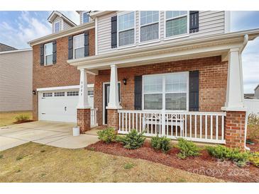 Charming two-story home with a brick facade, white porch, and attached two-car garage at 9203 Mackinaw Dr, Gastonia, NC 28056