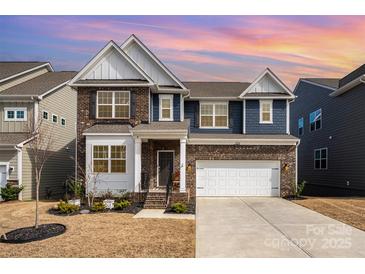 Stately two-story home boasts a brick and siding exterior, attached garage, and manicured landscaping at 1051 Lookout Shoals Dr, Fort Mill, SC 29715