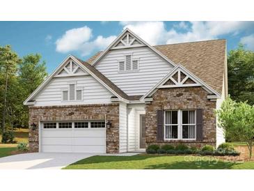 Charming two-story home featuring stone and white siding accents, a two-car garage and a well-manicured lawn at 1047 Rabbit Hill Ln, Monroe, NC 28110