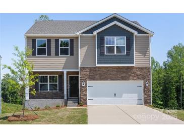Two-story home boasts a stone facade, light brown siding, a two-car garage and manicured front lawn at 111 Rustling Waters Dr, Mooresville, NC 28117
