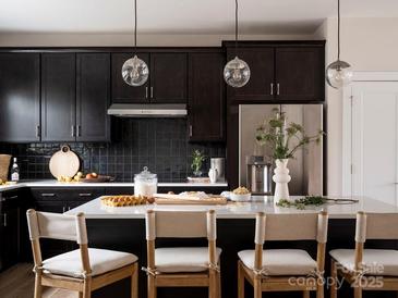 Modern kitchen features a large island with white countertops and stylish pendant lighting at 7003 Impulse Ct, Charlotte, NC 28205