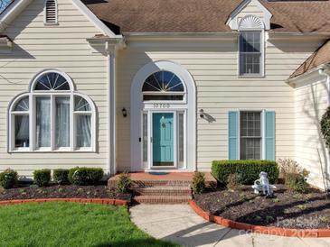 Close up view of a home's front door with turquoise shutters and manicured garden beds at 10700 Summitt Tree Ct, Charlotte, NC 28277