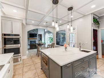 Open kitchen with island, marble countertops, stainless appliances and a coffered ceiling at 123 Yellow Jacket Cir, Mooresville, NC 28117