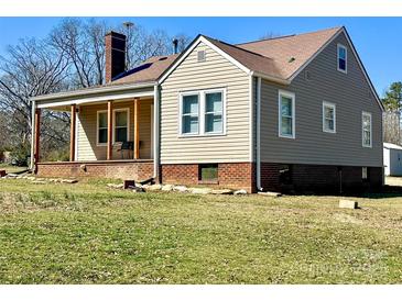 Charming two-story home featuring a cozy front porch, a brick chimney, and a mix of beige and gray siding at 2318 W Main St, Albemarle, NC 28001