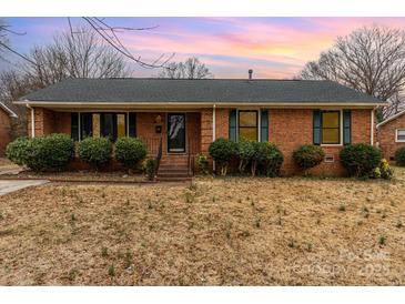 Charming single-story brick home featuring manicured bushes and neutral-colored trim at 4815 Carriage Drive Cir, Charlotte, NC 28205