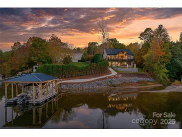 Waterfront home featuring a boat dock and lush foliage at sunset, reflecting on the serene lake at 6233 Riviera Run Estates Dr, Hickory, NC 28601