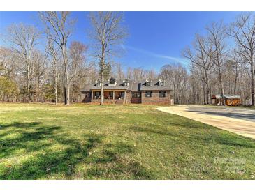 Charming brick home featuring dormer windows, a welcoming front porch, and a spacious front yard at 9414 Machado Dr, Indian Trail, NC 28079