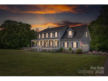 Charming two-story home with a large front yard, covered porch, and patriotic American flag waving in the breeze at sunset at 3929 Wexford Ln, Denver, NC 28037