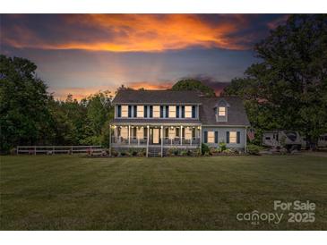 Charming two-story home with a covered porch, well-lit windows, and spacious front yard at sunset at 3929 Wexford Ln, Denver, NC 28037